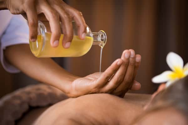 Oil poured into the therapist's hand before a back massage