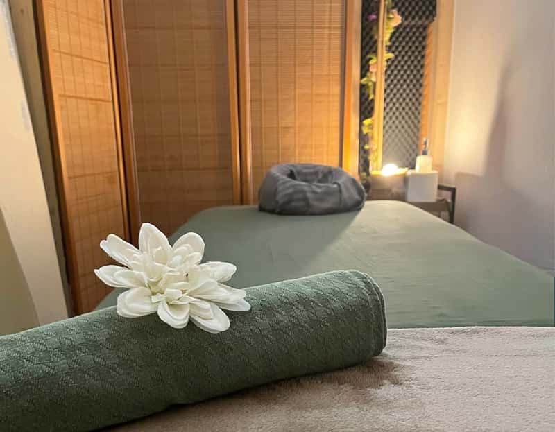 Massage table made up with a rolled towel and a white flower